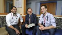 Three male doctors smile for a photo.